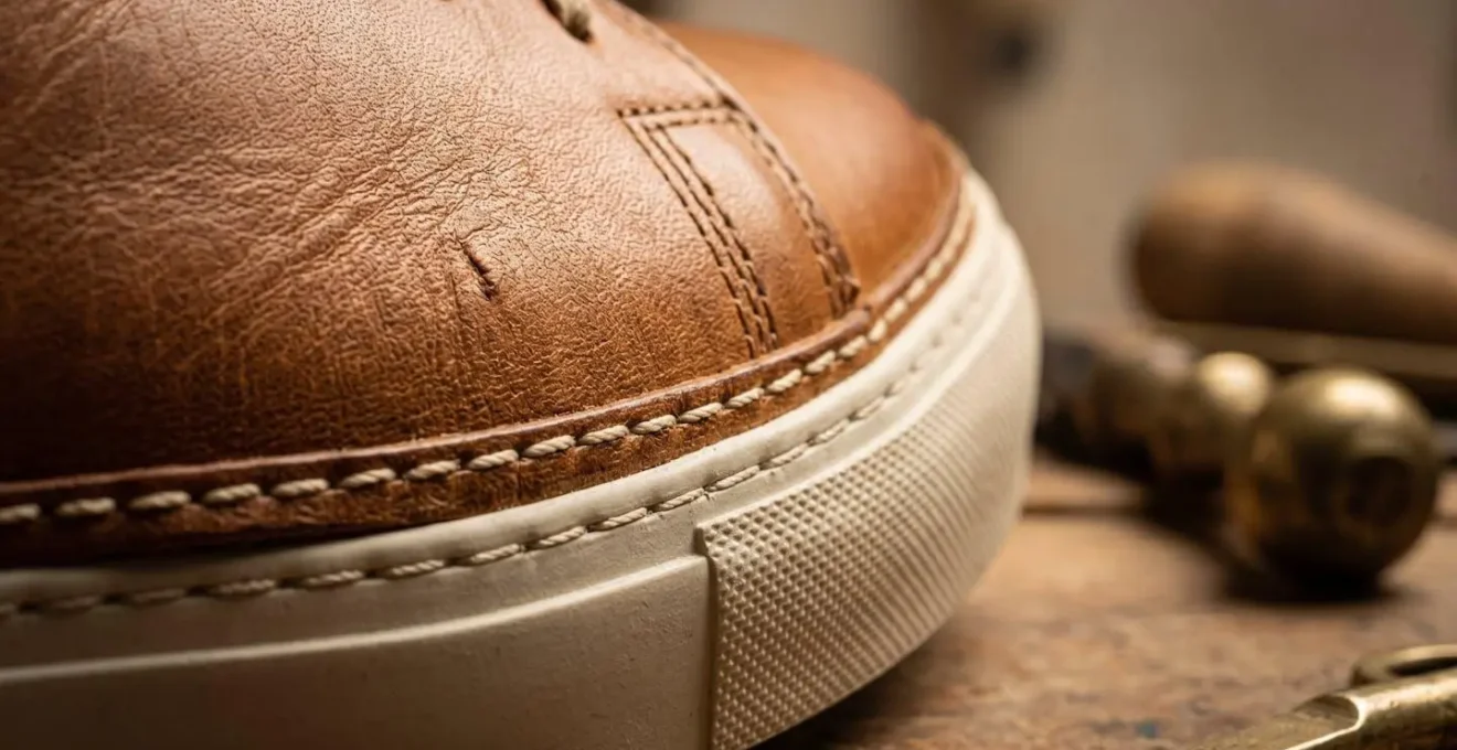 Dettaglio macro della costruzione artigianale di una sneaker in pelle con suola cucita