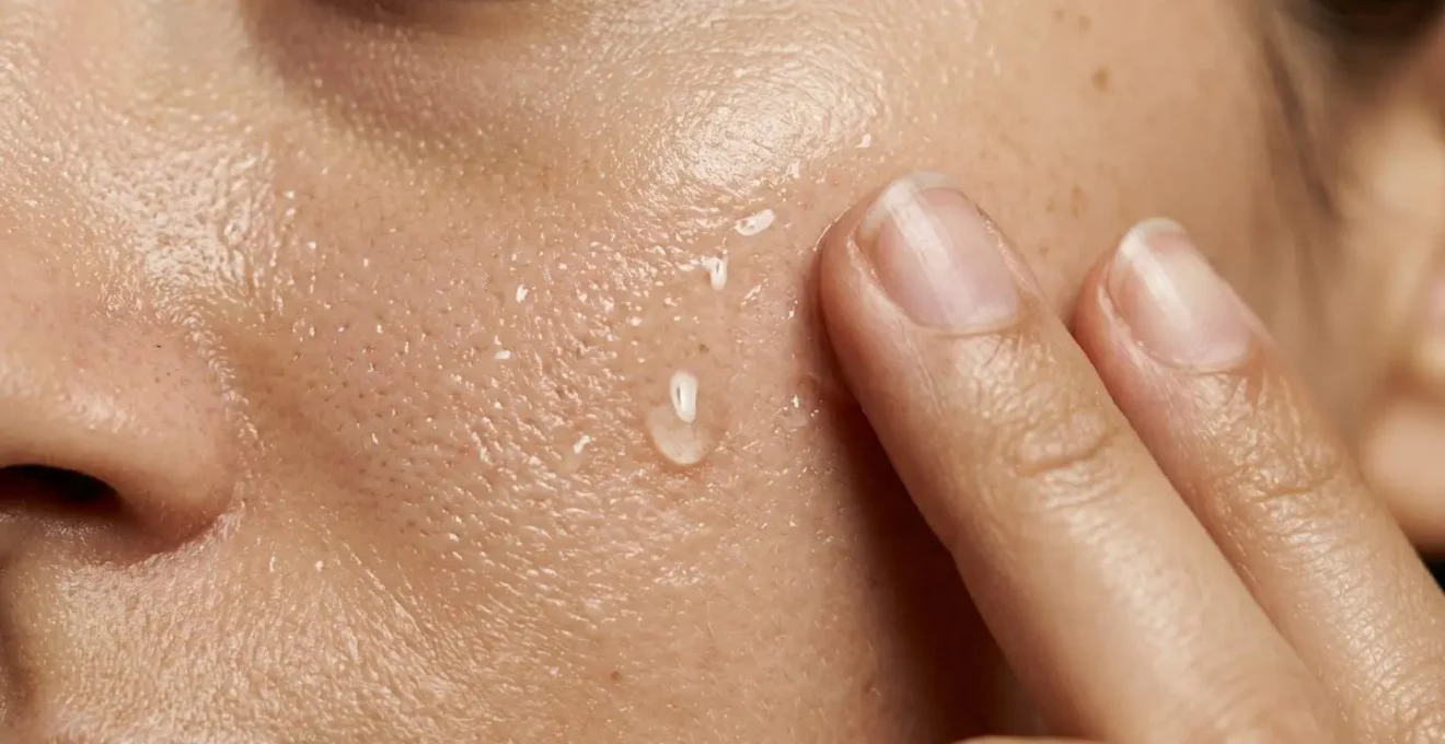 Dettaglio macro dell'applicazione di essence su pelle del viso con gocce d'acqua