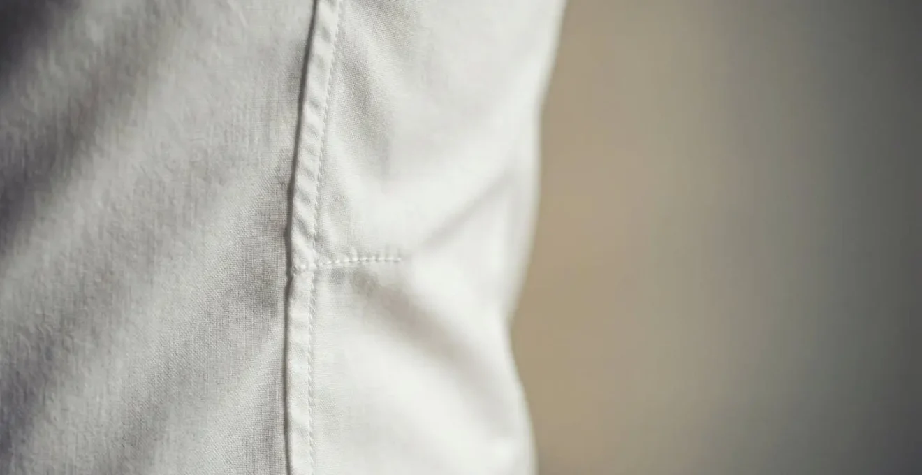 Dettaglio ravvicinato di una camicia slim fit bianca perfettamente aderente che evidenzia la vestibilità sartoriale e la cura dei dettagli