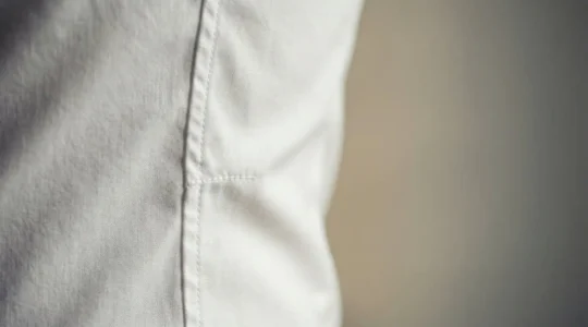 Dettaglio ravvicinato di una camicia slim fit bianca perfettamente aderente che evidenzia la vestibilità sartoriale e la cura dei dettagli