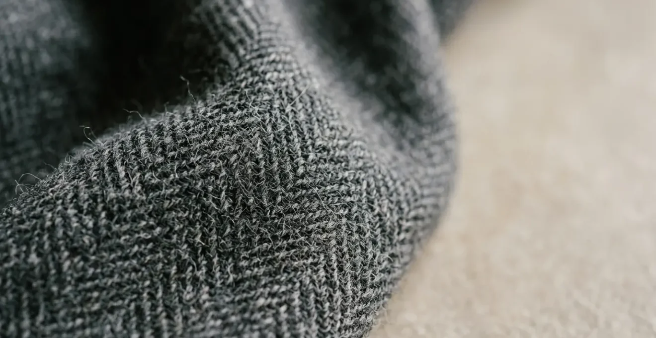 Dettaglio ravvicinato di tessuto di lana pregiato italiano con texture naturale e ricca profondità