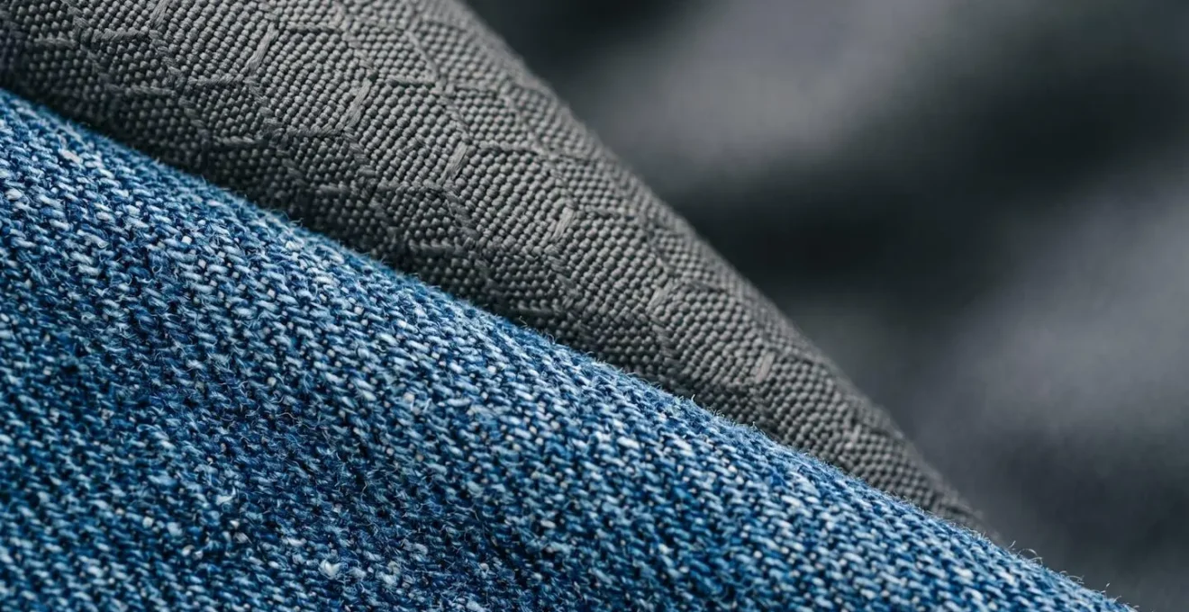 Dettaglio ravvicinato di tessuti tecnici resistenti per abbigliamento bambini con texture visibili di denim e materiali performanti